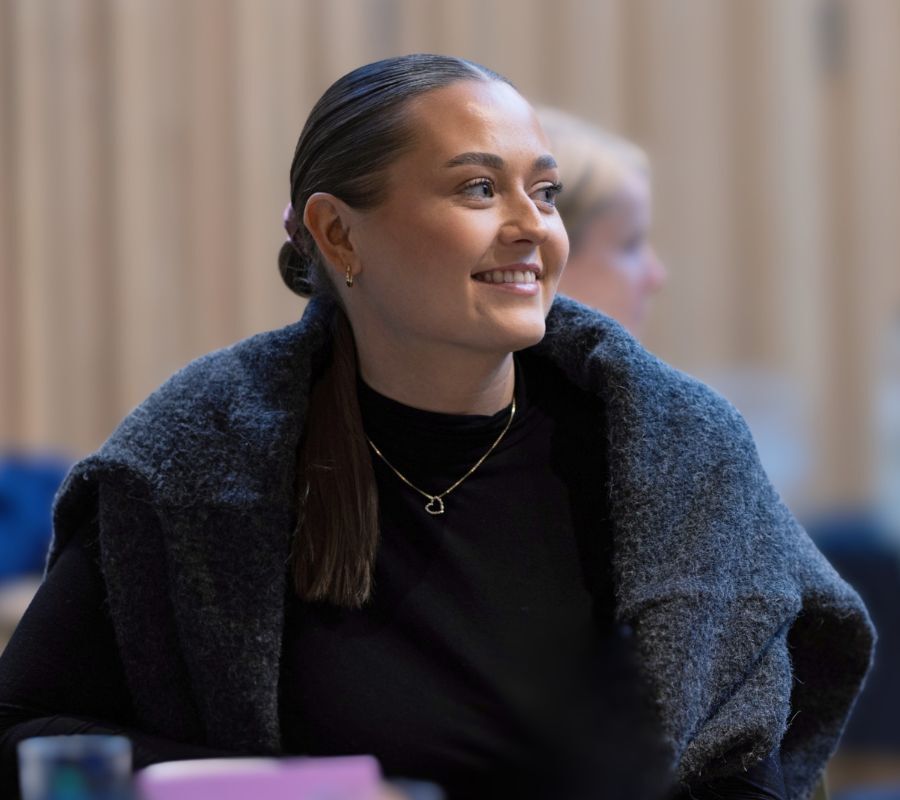 Professionellt lyssnande under ett affärsevenemang, som representerar kontinuerlig efterlevnad och uppkopplad kontroll i moderna organisationer.