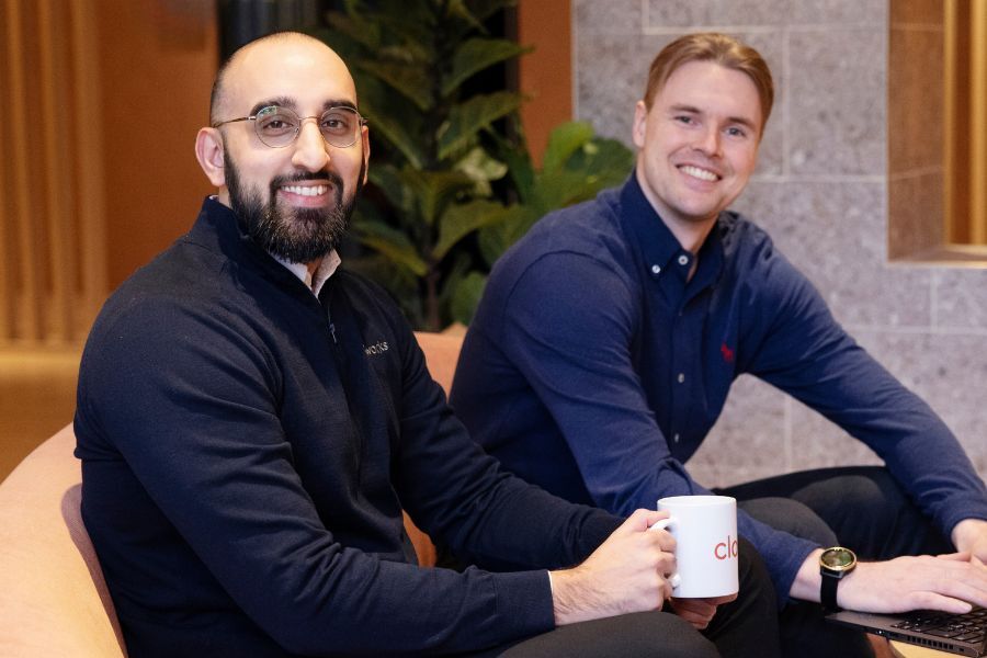 Två kollegor som sitter och ler mot kameran i ett mötesrum hos Cloudworks